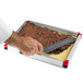 A hand using a knife to cut a chocolate mousse cake.