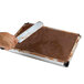 A person using a spatula to spread chocolate in a brown square baking tray.