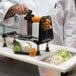 A person using the Bron Coucke Le Rouet Spiral Vegetable Slicer to cut vegetables on a counter.