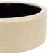 A beige stoneware ramekin with a black rim.