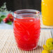 A Libbey tiki glass filled with red liquid on a table.