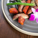 A Chef & Sommelier Geode stoneware dinner plate with food and a flower on it.