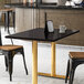 A black Art Marble Furniture Black Galaxy granite tabletop on a table with a white mug and two chairs.