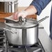 A person cleaning a Vigor stainless steel sauce pan on a stove.