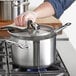 A hand using a sponge to clean a Vigor stainless steel sauce pan.