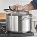 A person cooking with a Vigor stainless steel sauce pot on a stove.