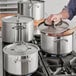 A man using a Vigor stainless steel sauce pot on a stove.