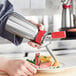 A person using an iSi stainless steel whipped cream dispenser to add whipped cream to a plate of food.