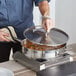 A person cooking food in a Vigor stainless steel saute pan on a stove.