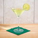 An Arcoroc martini glass with a green drink and a lime wedge on a napkin.