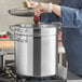 A woman using a Vigor SS1 Series stainless steel double boiler to dip a strawberry in chocolate.