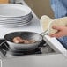 A person cooking bacon in a Vigor stainless steel non-stick fry pan.