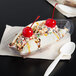 A clear plastic banana split boat filled with a banana split with cherries and sprinkles.