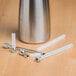 A stainless steel iSi injector tip with white plastic strips inside.