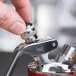 A hand holding a metal iSi decorator tip