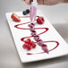 A hand with a pastry bag using iSi 3 Piece Decorator Tips over a plate of fruit.