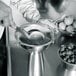 A person using an iSi stainless steel funnel with sieve insert to strain raspberries.