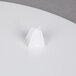 A Wilton white plastic cake separator plate with a white cake on a white surface.