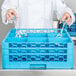 A chef using a Carlisle glass rack with extenders to wash wine glasses.