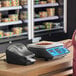 A woman using an AvaWeigh digital scale to weigh food on a deli counter.