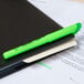 A Bic Brite Liner fluorescent green pen on a black notebook.