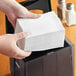 A person holding a box of white OneUp by Choice wide interfold dispenser napkins.