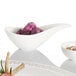 A white bowl with white sauce in it.