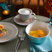 A Villeroy & Boch taupe porcelain saucer with a cup of coffee on a table with a plate of fruit.