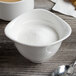 A white Villeroy & Boch porcelain sugar bowl on a table with a spoon inside.