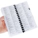 A person's hand holding The Bartender's Black Book with a spiral binding.