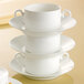 A stack of three Villeroy & Boch white bone porcelain bouillon cups on a white table.