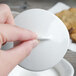 A close-up of a person's fingers holding a white Villeroy & Boch Dune sugar bowl lid.