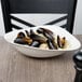 A white porcelain Villeroy & Boch Dune deep bowl filled with mussels on a table.