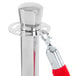 A Lancaster Table & Seating silver rope-style crowd control stanchion with red rope attached.