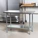 A stainless steel Advance Tabco work table with a galvanized undershelf.