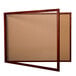A wooden enclosed bulletin board with a cork board in the middle.