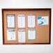 An Aarco enclosed cork bulletin board with a cherry finish.