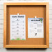 An Aarco natural oak enclosed bulletin board with cork.