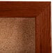 A cork bulletin board with a cherry frame.