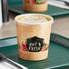 A Choice paper soup container with a clear lid on a tray.