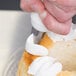 A person using an Ateco St. Honore piping tip to decorate a cake with a pastry bag.