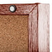 An Aarco cherry finish cork board with a screw in the corner.