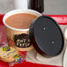 A tray with a bowl of soup and crackers with a black and white dotted lid on top.