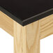 A close up of a black National Public Seating science lab table with wood grain.