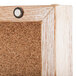 A close up of the cork board inside an Aarco Enclosed Hinged Display Case with a natural oak finish.