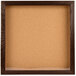 A cork board in a wooden frame with a walnut finish.