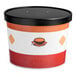 A large paper soup cup with a vented black lid and a colorful soup-themed design.