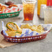 A brown plastic oval fast food basket filled with food and drinks on a table.