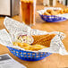 A blue Choice round plastic fast food basket filled with fried food and a side of coleslaw on a table.