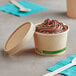 An EcoChoice Kraft paper food cup filled with chocolate ice cream and sprinkles on a counter.